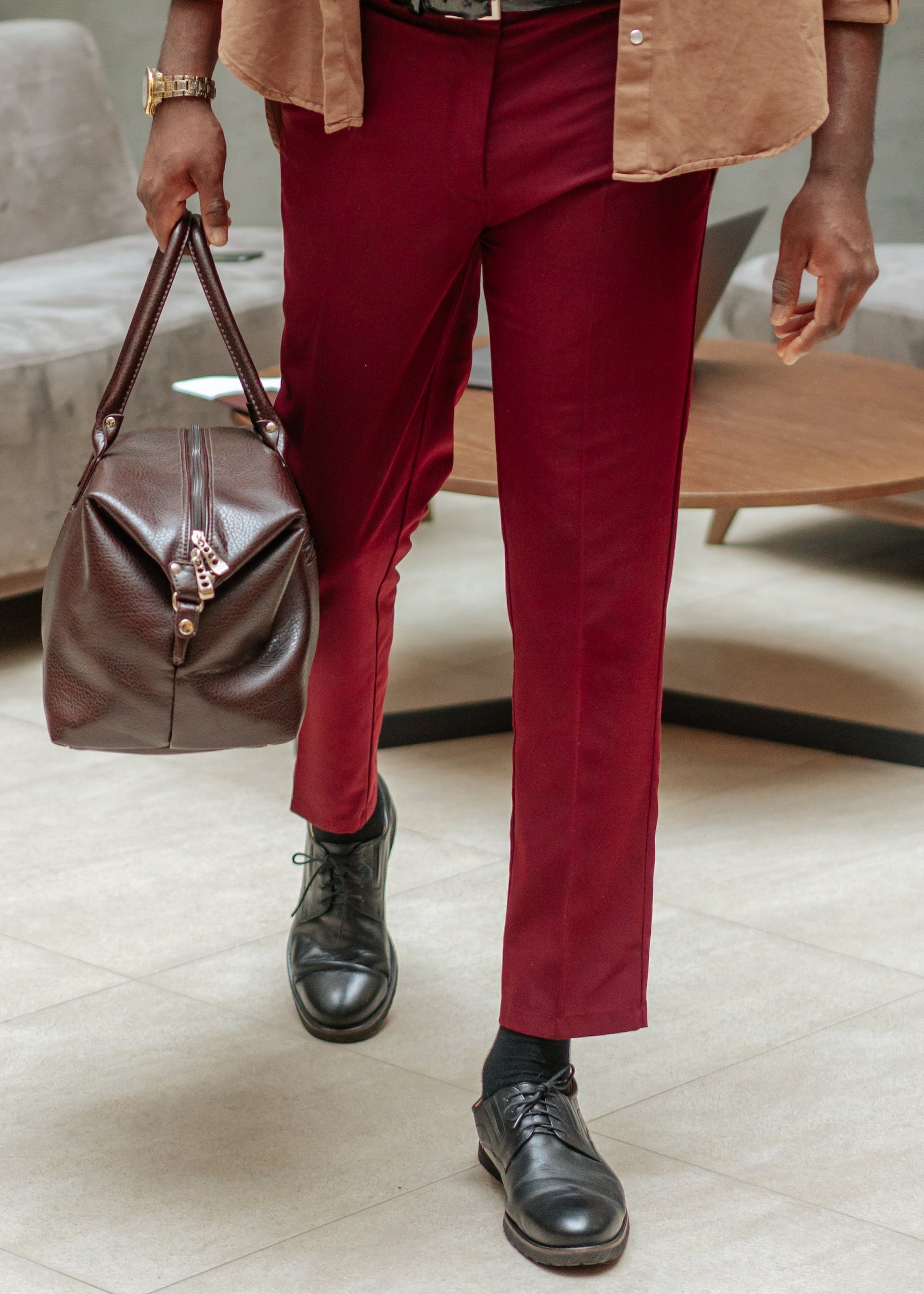 lopende man met rode broek en bruine leren tas