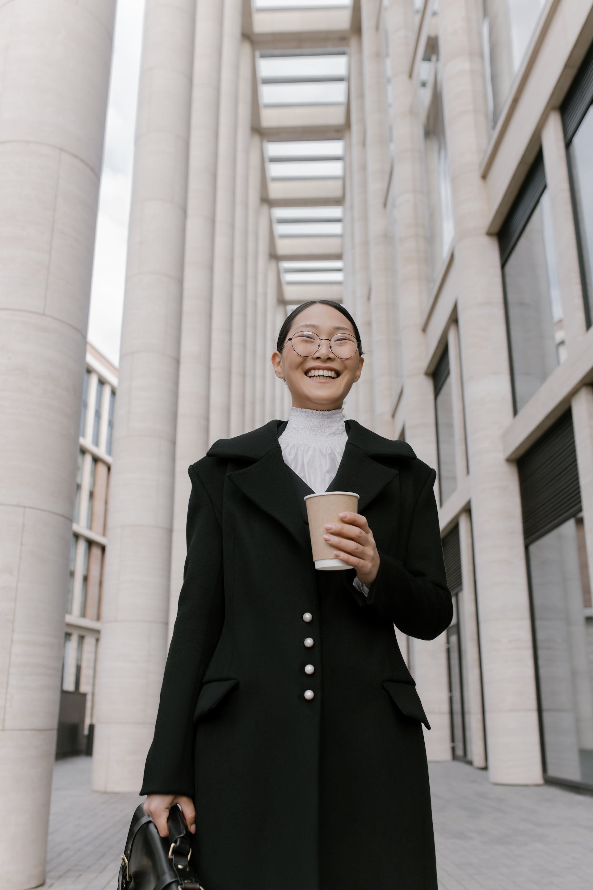 Neatly dressed woman smiling as she holds a coffee mug